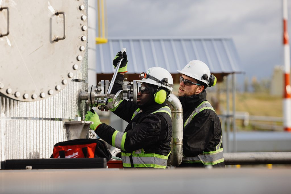 Two people fasten a gauge at the Arbios Chuntoh Ghuna facility